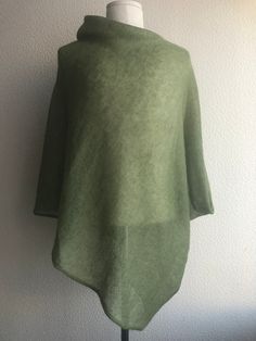 a green sweater is hanging on a mannequin headdress with a white wall in the background