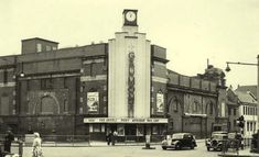 an old black and white photo of cars parked in front of a theater