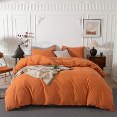 an orange comforter on a bed in a room with white walls and flooring