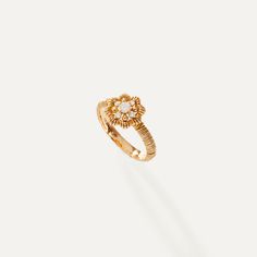 a gold ring with a diamond in the middle and a small flower on it's side