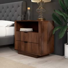 a bedroom with a bed, nightstand and plant in the corner on the side table