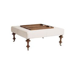 a white ottoman with wooden legs and a tray on top