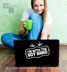 a woman sitting on the floor with her laptop and holding a cup in front of her