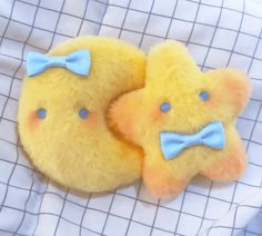 two yellow teddy bears with blue bows laying on a white bed sheet, next to each other