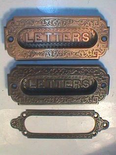 two old style door handles with the word letters written on one side and an ornate design on the other