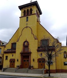 an old yellow church with a steeple and stained glass windows on the front door