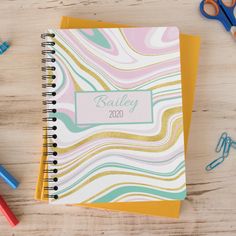 a spiral notebook with the name bailey on it next to scissors and crayons