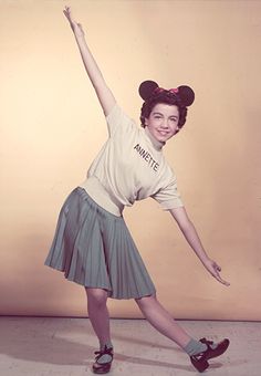 an old photo of a woman in mickey mouse ears and t - shirt with her arms outstretched