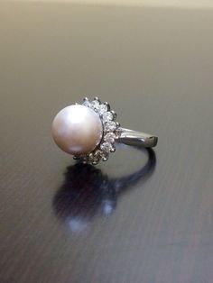 a pearl and diamond ring sitting on a table