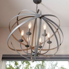 a chandelier with six lights hanging from it's center circle, in front of a window