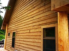 the side of a wooden house with wood siding and windows on it's sides