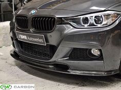 the front end of a silver bmw car parked in a garage with other cars behind it