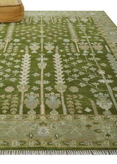 a green rug with an intricate design on the bottom and fringes around the edges