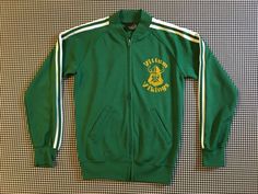 1980's, "Vittum Vikings" track jacket, in green with white and yellow, Young Men's size Medium, Women's size Small.  100% polyester.  Made for HIgh Five.  Zip front.  Front pockets.  There are a couple light snags, see ninth picture, an there is a small dot on the front, see last picture, otherwise in great condition.22.75" long, shoulder to bottom17.25" underarm to underarm16.5" across waist12.5" across bottom25.5" shoulder plus sleeve, neckline to wrist10" drop, shoulder to underarm Green Cotton Sporty Track Jacket, Green Cotton Track Jacket, Retro Green Track Jacket For Streetwear, Vintage Green Outerwear For Sports, Vintage Green Track Jacket For Winter, Green Retro Sports Outerwear, Retro Green Outerwear For Sports, Green Retro Outerwear For Sports, Polyester Pants