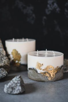 two white candles sitting next to each other with gold leaf decorations on top of them