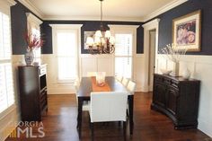 a dining room table with white chairs and dark wood floors