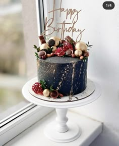 a birthday cake sitting on top of a white pedestal next to a window sill