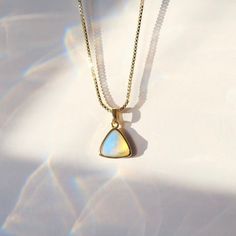 C R Y S T A L ∙ P E N D A N T ∙ N E C K L A C E Embrace the ethereal beauty of the opal with this dainty pendant necklace, whispering a touch of magic into your everyday. This captivating gemstone shimmers with flashes of rainbow fire, capturing the ever-changing essence of moonlight and dreams. Opal is beautiful blueish white stone is known for it's ability to encourage: Inspiration, Creativity, and Emotional Healing. * Design: Triangle Crystal Pendant - Box Chain Necklace & Beaded Necklace * Material & Finish: 18K Gold Plated Brass * Pendant: Faceted Triangle Shape * Pendant Size (Approx.): 10 x 10 mm | 0.375 x 0.375 in * Necklace Length - 3 Options: 16in, 18in, 20in ** Your necklace may vary slightly due to the uniqueness of the stone B I R TH S T O N E ∙ A N D ∙ Z O D I A C * Birthston Gift Moonstone Necklace With Adjustable Chain, Gold Moonstone Necklace As Gift, Gold Clavicle Chain Necklace With Moonstone, Gold Moonstone Necklace For Gift, White Brass Necklace For Gift, White Dainty Box Chain Necklace, Spiritual Box Chain Necklace As Gift, Spiritual Box Chain Necklace Gift, Brass Gemstone Necklace For Gift