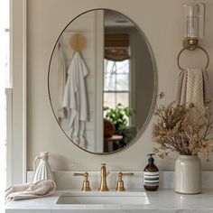 a bathroom sink with a round mirror above it