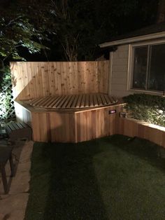 a wooden bench sitting in the middle of a yard next to a house at night