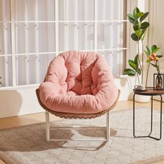 a pink chair sitting on top of a wooden floor next to a potted plant