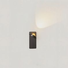 a wall mounted light on the side of a white wall next to a black object