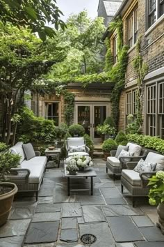 an outdoor living area with couches, tables and potted plants