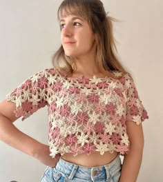 a woman with her hands on her hips wearing jeans and a crochet top