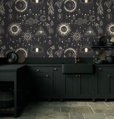 a kitchen with black cabinets and an artistic wallpaper