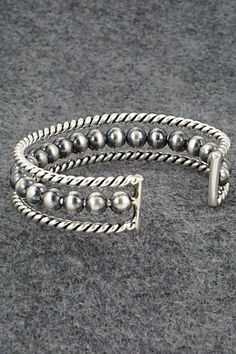 This darkened sterling silver bracelet featuring a row of round beads was made by Navajo silversmith Elaine Tahe.Size: 5 1/8" (will fit up to a 6 1/4" wrist)Gap: 1 1/8"Width: 1/2"Free shipping on all orders! We ship with USPS and always include tracking. All orders ship within a day of payment.Returns are accepted up to 30 days after you receive your order. Just send us a message. Our shop offers cash back or store credit. The item must be returned in new condition. Southwestern Silver Bracelet With Round Beads, Southwestern Style Silver Bracelets With Round Beads, Southwestern Style Silver Bracelet With Round Beads, Southwestern Silver Hand-strung Bracelets, Sterling Silver Bracelet, Native American Jewelry, Free Jewelry, Sterling Silver Bracelets, Round Beads