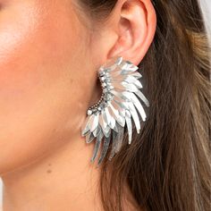 a close up of a person wearing large silver earring with leaves on it's sides