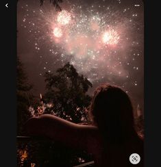 a woman is looking at fireworks in the sky