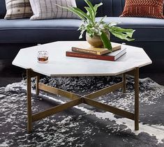 a living room with a blue couch, coffee table and plants on the end tables