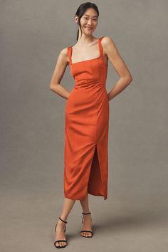 a woman in an orange dress poses for the camera