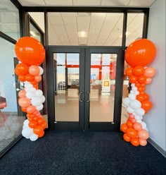 an entrance decorated with orange and white balloons