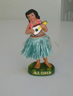 a small figurine with a hula skirt holding a banana