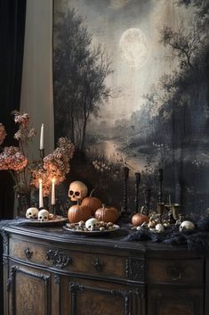 a table topped with skulls and candles next to a wall covered in a painting behind it