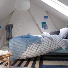 a bed in a room with a skylight above it and pillows on the floor