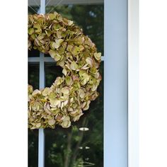 a wreath hanging on the front door of a house with trees in the back ground