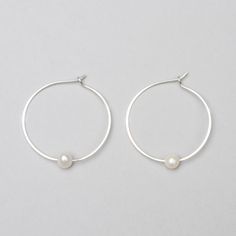 These timeless pearl hoops are made by hand and have a slight irregularity to . Wear this classic shape daily or for a night out on the town. These make a great gift, easily worn for years by earring wearers of all ages and tastes. A variation of our Classic Hoops with a pearl. Product Details: -Available in solid sterling silver or 14k gold fill -Hammered 1.25in hoop with a hook clasp sold as a pair. -Pearl is an AAA-grade freshwater pearl that measures 5-6mm. All items are hand made to order, Small Hoop Pearl Earrings For Everyday, Classic Hoop Pearl Earrings As Gift, Modern Pearl Hoop Earrings As Gift, Classic Pearl Hoop Earrings As Gift, Classic Pearl Hoop Earrings For Anniversary, Minimalist Small Hoop Pearl Earrings For Anniversary, Everyday Small Hoop Pearl Earrings, Everyday Sterling Silver Pearl Earrings, Classic Pearl Charm Hoop Earrings For Anniversary