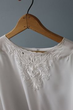 Vintage romantic neo Victorian semi sheer blouse in porcelain white color. Beautiful detailed embroidered flowers cut out bib front. Bishop sleeves with embroidered cut out shoulder detail. ⊰ Measurements:  Fits like medium, large: 15" shoulders 42" bust 24" length 23" sleeves Tag: Christie & Jill Circa 1980s Condition: excellent! ⊰ Visit the shop: adriancompany.etsy.com ⊰ Instagram: @adriancovintage @the_veiled_ghost Elegant Spring Blouse With Embroidered Neckline, Elegant Summer Blouse With Embroidered Neckline, Elegant Blouse With Embroidered Neckline For Spring, Spring Wedding Tops With Embroidered Neckline, Feminine Floral Embroidered Tops For Weddings, Feminine Embroidered Tops For Wedding, Feminine Embroidered Wedding Tops, Feminine Floral Embroidered Wedding Tops, Elegant Wedding Blouse With Embroidered Neckline