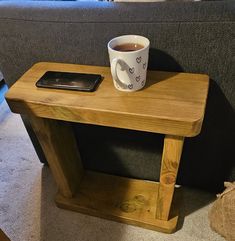 a cup of coffee sitting on top of a wooden table next to a phone and remote control