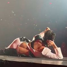 a woman laying on top of a stage next to a man with his head in his hands