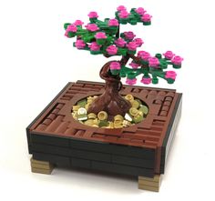 a small tree made out of legos sitting on top of a wooden box filled with coins