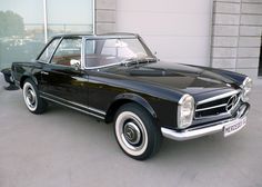 an old black car parked in front of a building