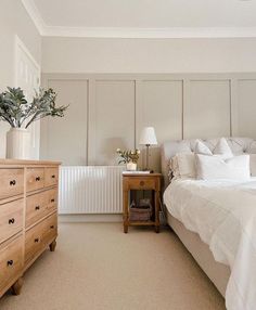 a bedroom with a bed, dresser and plant in the corner on top of it