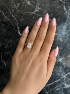 a woman's hand with pink manicured nails and a diamond ring on her finger