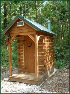 a small wooden outhouse in the woods