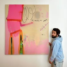 a man standing in front of a painting on the wall next to a white wall