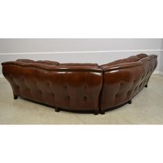 a large brown leather couch sitting on top of a white carpeted floor next to a wall